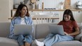 Mother and daughter sit on couch with laptops