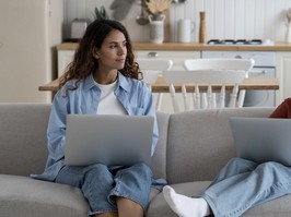 Mother and daughter sit on couch with laptops