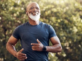 Happy black man running in park with music, smile and mockup in nature, garden and workout. Senior male, outdoor runner and motivation for fitness, energy and healthy exercise training with earphones