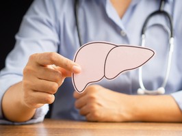 Doctor hand holding a liver shape made from pink paper while sitting in the hospital. Medical and healthcare concept. Close-up photo