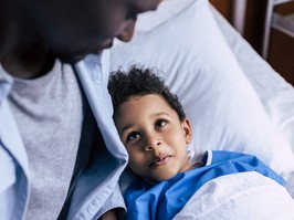Young boy looking up to his father from a hospital bed