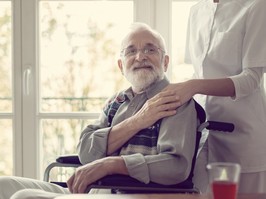 Senior patient in nursing home with helpful nurse in white uniform