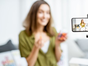 Young woman recording her vlog about healthy eating and nutritional supplements, close-up on a phone screen. Preventive medicine and influencer marketing concept