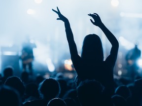 Woman with hands up dancing and having fun during concert show on summer music festival. Youth and celebration concept.