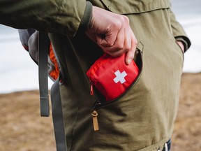 A tourist person puts in his pocket a first-aid kit for a hike, mobile medical care for an injury, a red box with tablets, an ambulance kit. High quality photo