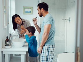 Parents, child and brushing teeth in family home bathroom while learning or teaching dental hygiene. A woman, man and kid with toothbrush and toothpaste for health, cleaning mouth and wellness