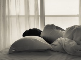 Young woman lying in bed, looking towards through the window - black and white photo.