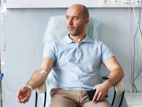 Adult man sitting in chair with IV drip during treatment session in clinic