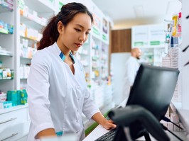 Female pharmacist using computer while working in a pharmacy.