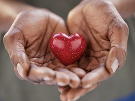 Close up of black woman hands holding a small red heart. Small heart in the hands of a african woman. Solidarity, charity and responsibility concept.
