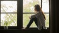 Thoughtful girl sitting on sill embracing knees looking at window, sad depressed teenager spending time alone at home, young upset pensive woman feeling lonely or frustrated thinking about problems