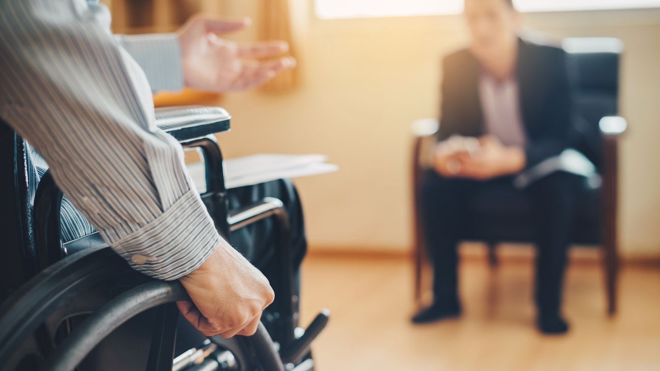 Man on wheelchair with his boss. After car accident and rehabilitation, a businessman can return to work again.