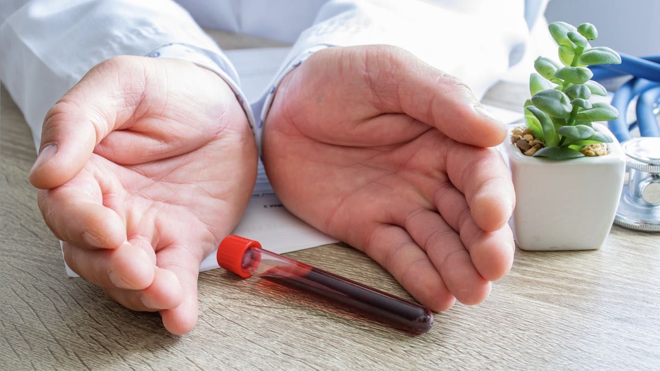 Protection, treatment, prevention and patronage health in hematology in blood health against diseases, pathologies, oncology concept photo. Doctor surrounded lab tube with blood with hands on desk