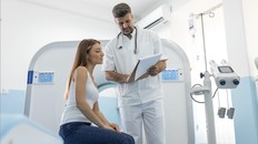 Male doctor giving information to woman before MRI scan examination. Magnetic resonance imaging technology in specialized medical clinic.