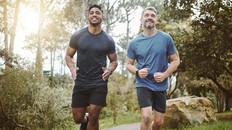 Running team, fitness and men in forest with cardio, athlete with personal trainer for support in sports and health.