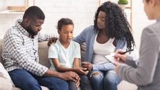 Little black girl and her parents at psychologist consultation - stock photo
