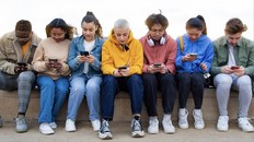 Panoramic image of multiracial group of teen college students ignoring each other looking at mobile phone checking social media. Gen z and technology concepts.