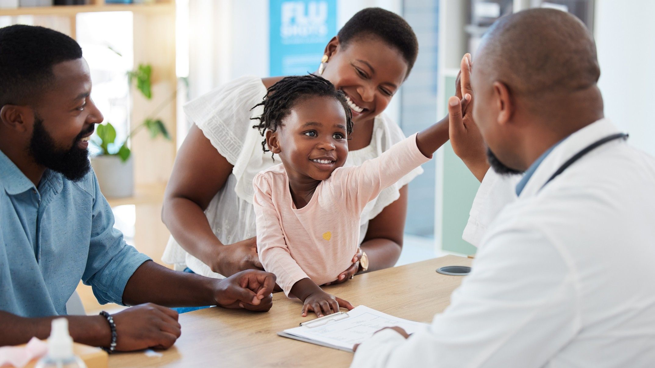 Black family smiling and talking with a black doctor. Mother, father and daughter.