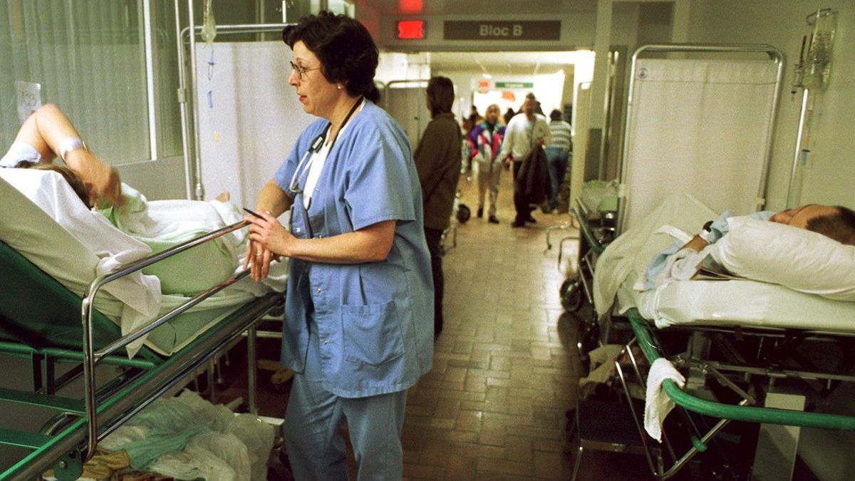 Nurse tending to a patient in the hallway of a hospital. Nurse talking to patient in hospital bed.