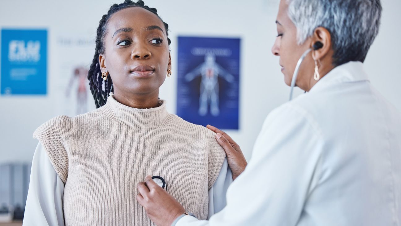 Black woman in medical exam. Doctor listening to her heart.