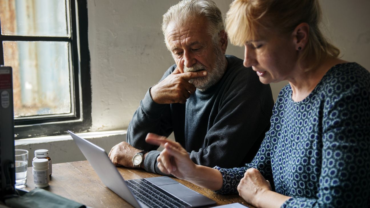 Elderly couple looking at a laptop together. Weighing healthcare options.