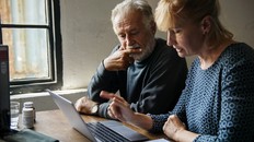 Elderly couple looking at a laptop together. Weighing healthcare options.