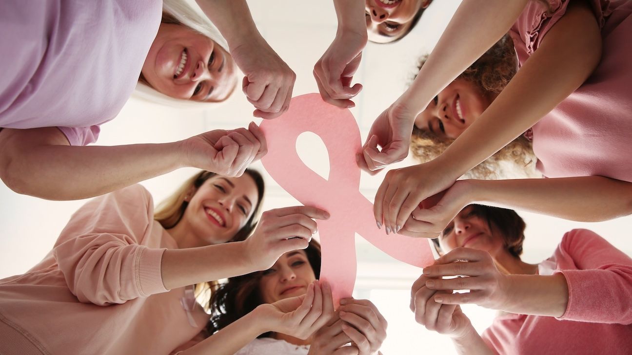 Women holding pink paper ribbon, bottom view. Breast cancer awareness concept