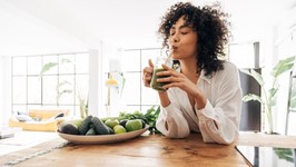 woman enjoying a green juice. young black woman drinking green juice.