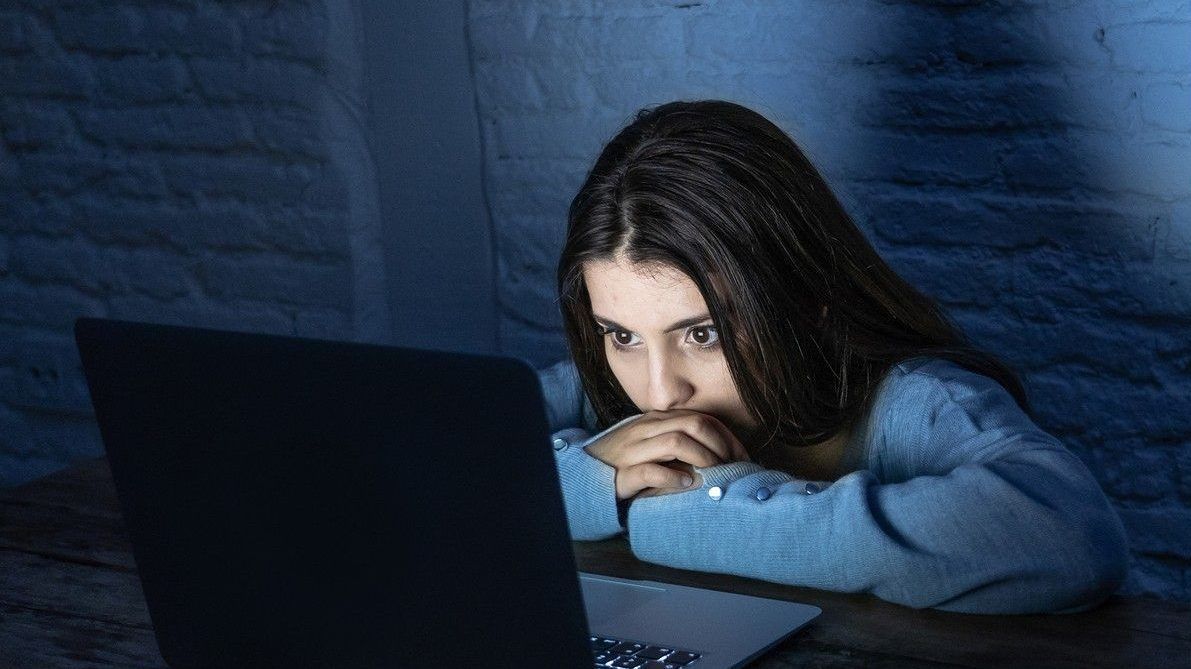young woman looking at computer screen in the dark.