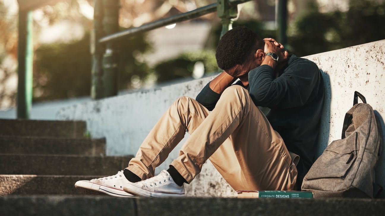 Young black man with his head in his hands. Young man feeling stressed.
