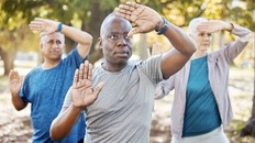 Three older adults doing Tai Chi in a park on a sunny summer day