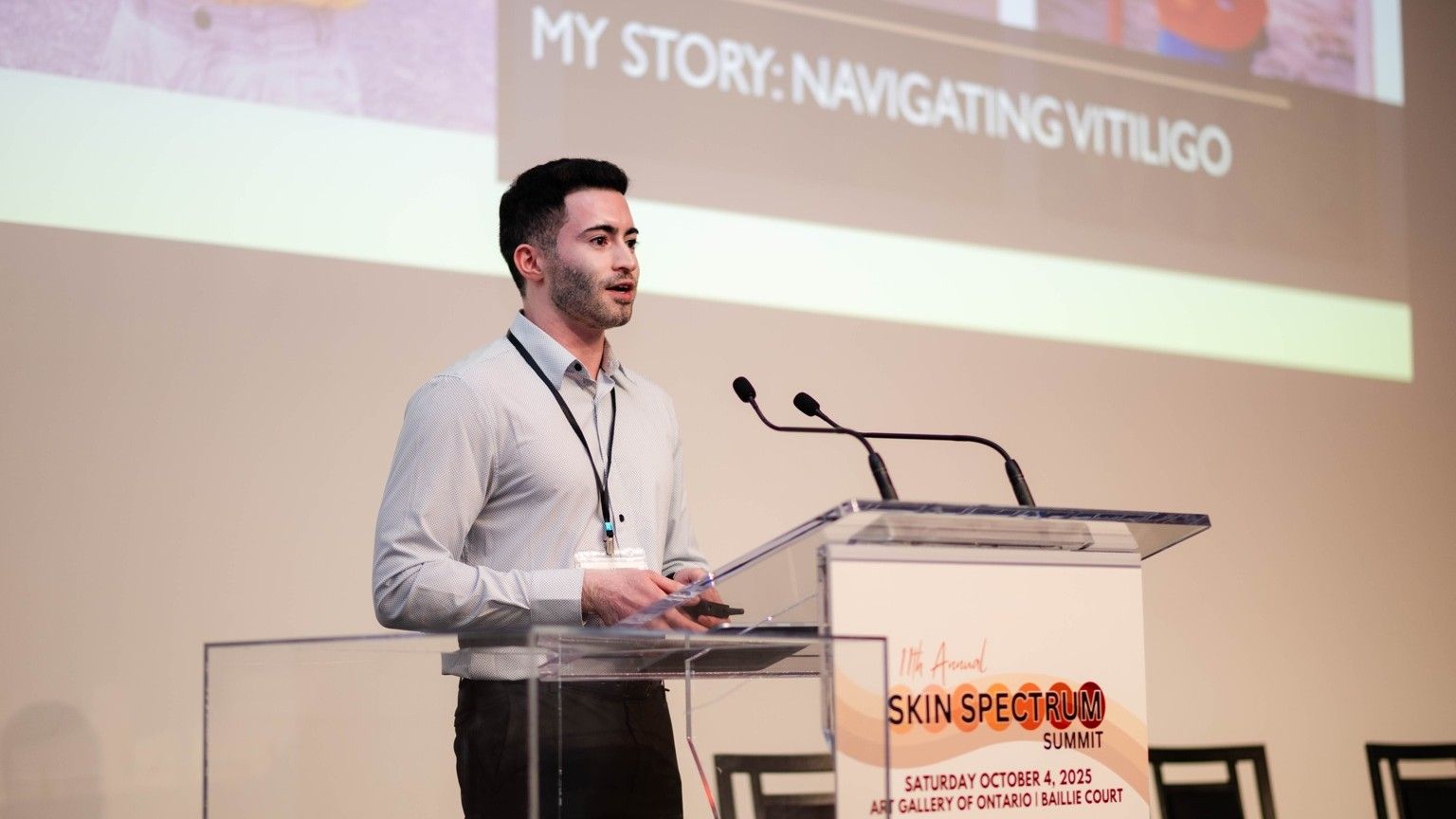 Man with vitiligo speaks at podium.