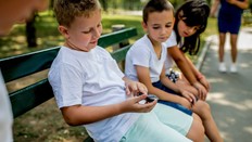 Boys on park bench test blood sugar for diabetes care.