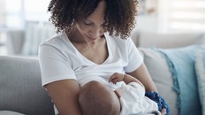 Love, living room and mother breastfeeding her baby for health, nutrition and wellness at home. Bonding, care and young woman nursing or feeding her newborn child milk on the sofa in the family house