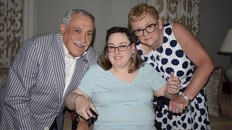 A father, daughter, and mother pose for a photo, smiling.