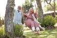 Mature couple outdoors, man pushing woman on swing