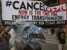 A protester, wearing a Halloween mask, stands near a protest banner during a rally near the Presidential Palace to protest the country's use of coal to power energy generation power plants which according to them has contributed to pollution Saturday, Oct. 10, 2015 in Manila, Philippines. The protesters are urging the Government to do more to reduce Greenhouse gas emissions which allegedly contributes to global climate change.