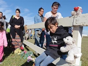 Avary Cyr, bottom right, and others look down during a prayer at a memorial walk for the Regina Indian Industrial School cemetery on Pinkie Road about 1.5 KMs north of Sakimay gas station west of Regina, Sask. on Saturday Oct. 10, 2015. Various First Nations want the residential school cemetery to be recognized and protected as a heritage site.