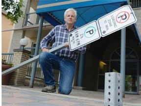 Bill Bolstad poses in front of his condo building in Regina on Sunday, Aug. 16, 2015. Bolstad holds a sign, to which only hours before his bike was locked. Someone apparently unbolted the sign from its base, and made away with the bike in broad daylight. (Michael Bell/Regina Leader-Post)