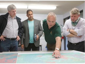 John deBruin, Senior Fire Manager, second from right, explains a fire map to Prime Minister Stephen Harper, left to right, MP for Desnethe-Missinippi-Churchill River Rob Clarke, and MP for the federal riding of Prince Albert Randy Hoback during a visit to the wildfire management centre in La Ronge, Sask., fire hall on Friday, July 24, 2015.