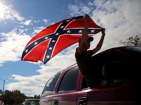 Chance White waves a Confederate battle flag as he drives away from Roseburg Regional Airport in Roseburg, Ore., Friday, Oct. 9, 2015.