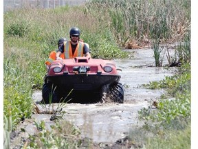 The city of Regina's Burton Gerspacher (front) and Logan Lang spray standing water just north of the city for mosquito larvae.