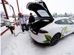 Coun. Wade Murray, left, looks on as James Dennis of Sun Country Highway plugs his electric vehicle into a charger at the Best Western Seven Oaks Inn in Regina on Feb. 6, 2015. TROY FLEECE / Regina Leader-Post