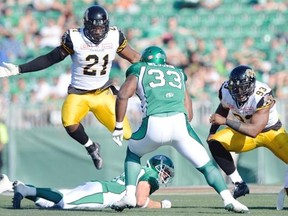 Hamilton Tiger-Cats linebacker Simoni  Lawrence (#21) jumps in the air to try stop Saskatchewan Roughriders running back Jerome Messam (#33) at Mosaic Stadium in Regina on Sunday.