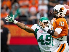 Lions quarterback Jonathon Jennings (10) passes while being rushed by Saskatchewan Roughriders’ Jeff Knox Jr. on Saturday (Darryl Dyck/The Canadian Press)