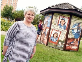 Maureen (Chick) Baker stands in front of the mural commemorating her mother, baseball player Mary (Bonnie) Baker that is being unveiled Saturday.  Artist Carly Jaye Smith is in the background working on the mural.