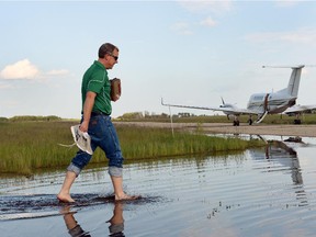 Saskatchewan Premier Brad Wall removed his socks and shoes and stepped across a flooded runway at the Melville airport to board a flight back to Regina after an aerial tour of flood-ravaged southeast Saskatchewan on July 02, 2014.