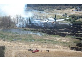 A water bomber flies above a field where fire crews work in the LaRonge area in this July 1, 2015 handout photo from the Saskatchewan Ministry of Environment.