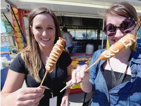 Paige Kreutzwieser (left) and Ashley Martin try out a Lobster corn dog while on a tour of unique concession food at the Queen City Ex in Regina.