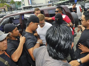 Lindsey Petersen, center, is escorted by police as he arrives at court in Kota Kinabalu, in eastern Sabah state on Borneo island, Malaysia, Friday, June 12, 2015.